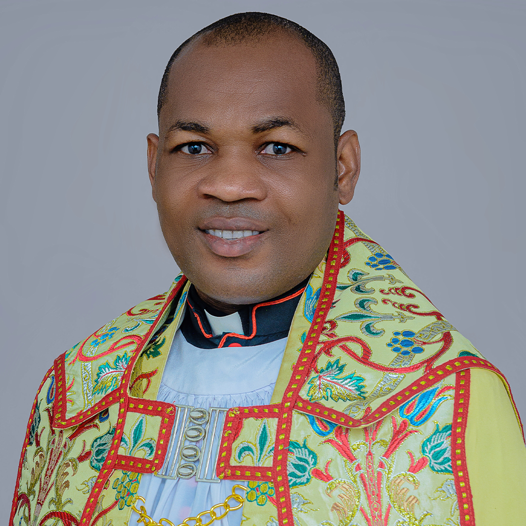 The Venerable Alex Uzor, smiling, in an embroidered cope fastened with a silver clasp over a white surplice.