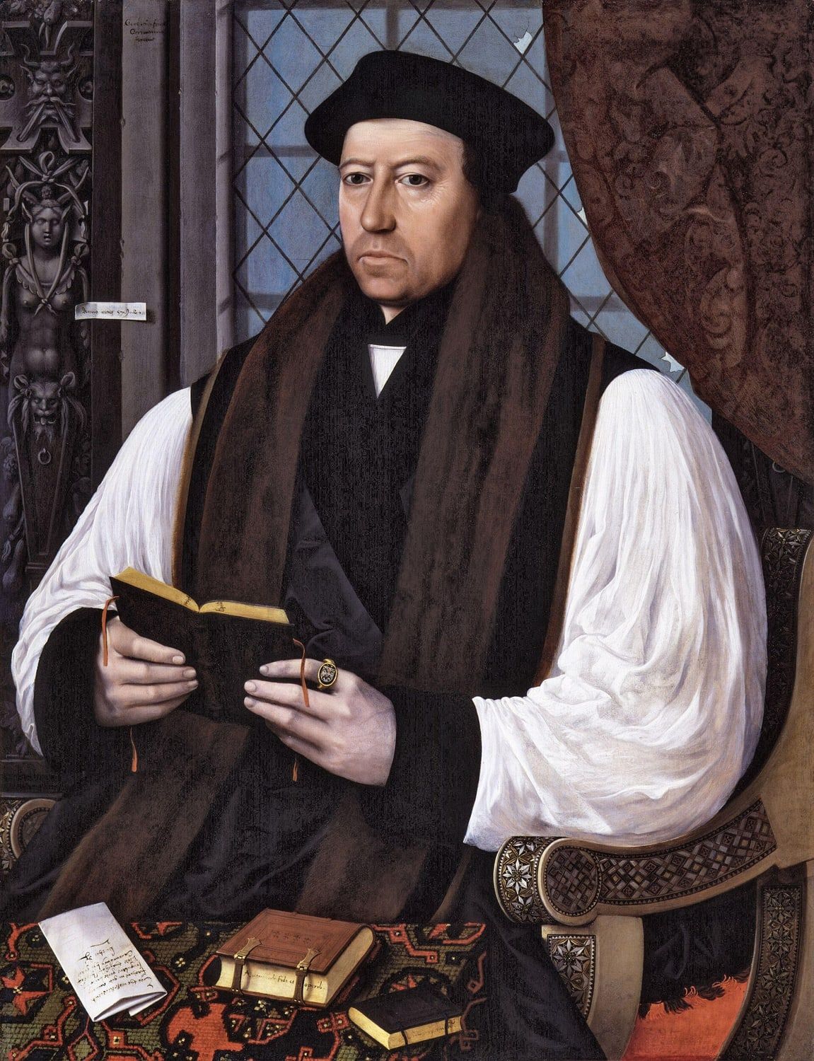 Portrait of Thomas Cranmer in a black cap and white sleeves, seated and holding a small book, painted in 1545.
